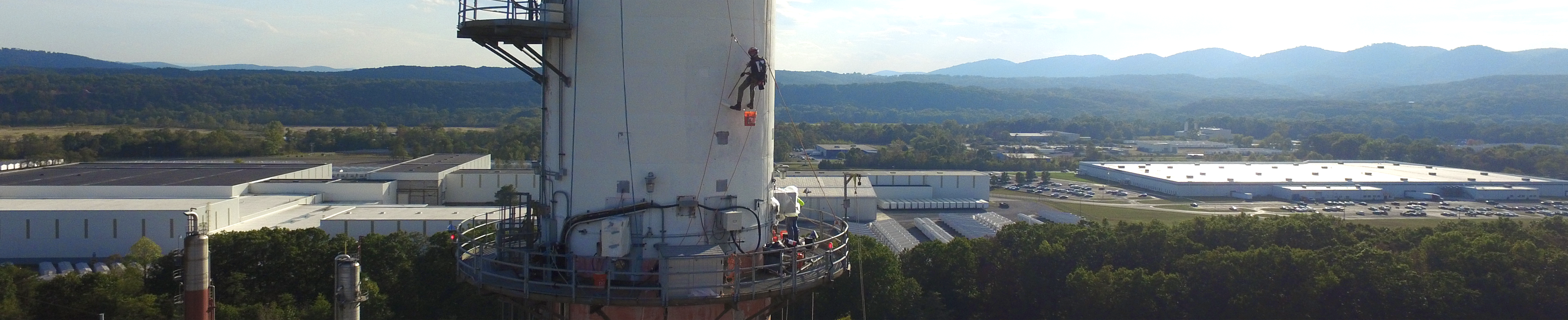crew using swing stage access approach in order to paint Industrial chimney at height